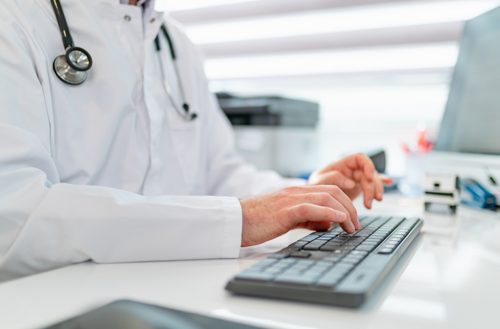 A doctor typing on their keyboard at their desk